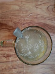 Warm orange drink and stainless steel spoon in a glass cup on a wooden table