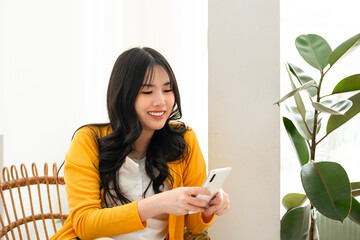 Young woman sitting in cafe looking at  smartphone reading or writing text message.