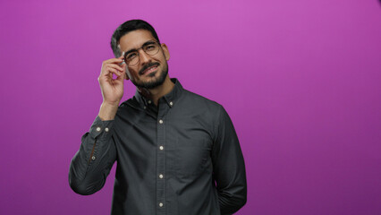 Man smiling confidently against a vibrant pink background in a portrait with glasses and dark hair wearing a casual shirt creating a stylish and modern composition
