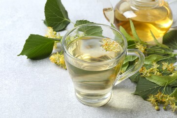 Green tea with fragrant linden in transparent cup on gray background