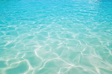 Fototapeta premium Clear turquoise ocean water with shimmering light reflections and gentle ripples over white sandy seabed, creating a serene tropical sea landscape perfect for evoking tranquil summer vacation, beach t