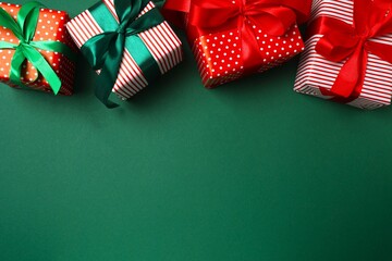 The holiday gifts decorated with bows and ornaments arranged on a green background, creating a...
