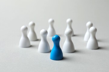 Blue pawn among white ones on the table. The concept of difference and uniqueness