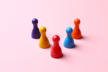 Colorful pawns on light pink background. Concept of Diversity, Inclusion and Equality, space for...