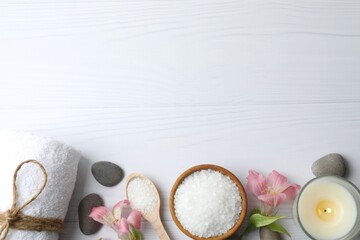 Top view of spa stones with candle, bath salt and towel on white wooden background with copy space....