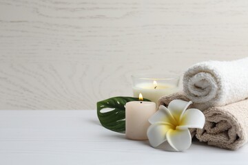 Spa composition with towels, flower and candles on wooden table. Spa and beauty treatments
