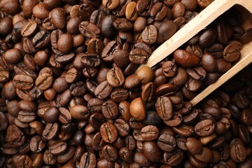 Aromatic coffee beans and wooden scoop as background, top view