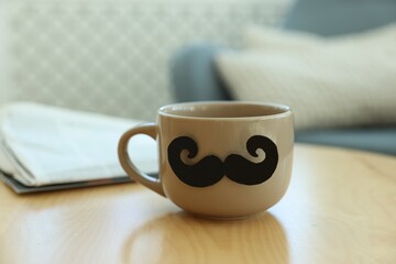 Happy Father's Day. Cup with mustache on wooden table indoors, closeup