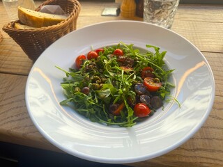 Delicious dish with tomato, avocado, stracciatella cheese and greens on a restaurant table