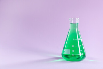 Conical flask with green liquid on lilac background. Space for text