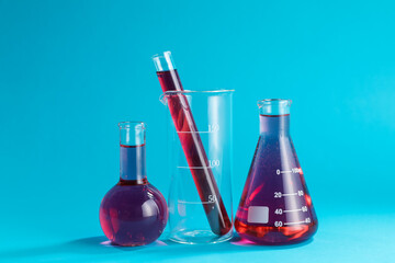 Laboratory glassware with color liquid on light blue background