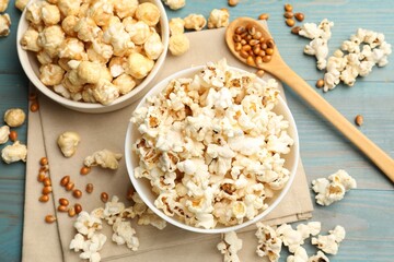 Tasty popcorn and corn kernels on light blue wooden table, flat lay