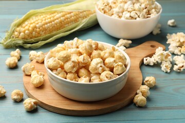 Tasty popcorn and corncob on light blue wooden table, closeup