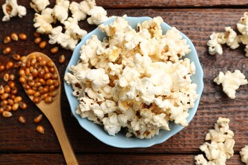 Tasty popcorn and corn kernels on wooden table, flat lay