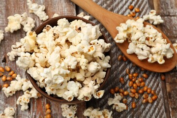 Tasty popcorn and corn kernels on wooden table, flat lay