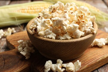 Tasty popcorn and corncobs on wooden table, closeup