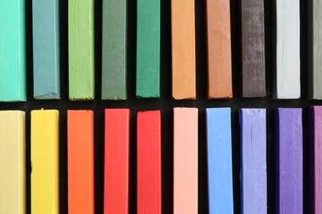 Colorful chalk pastels on black table, top view