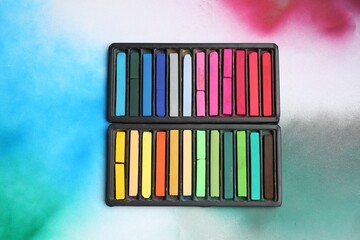 Colorful chalk pastels in trays on color background, top view