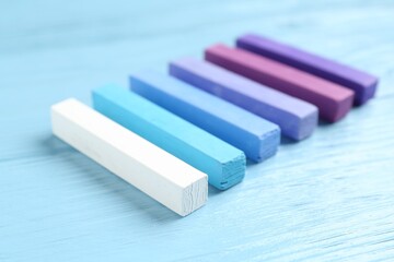 Colorful chalk pastels on light wooden table, closeup