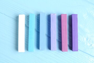 Colorful chalk pastels on light wooden table, flat lay