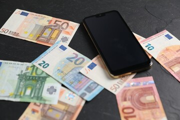 Smartphone and money on black table, closeup