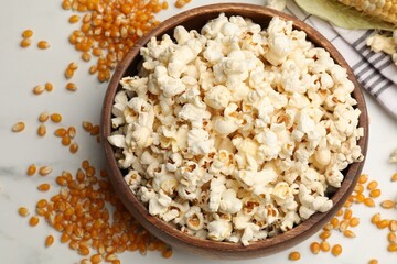 Tasty popcorn and corn kernels on white table, flat lay