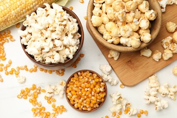 Tasty popcorn and corn kernels on white table, flat lay