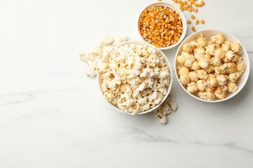 Tasty popcorn and corn kernels on white table, flat lay. Space for text