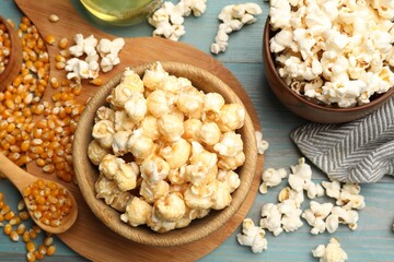 Tasty popcorn and corn kernels on blue wooden table, flat lay
