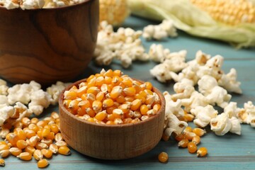 Corn kernels and tasty popcorn on blue wooden table, closeup
