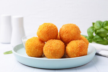 Delicious fried croquette balls on light tiled table, closeup