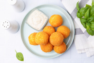Delicious fried croquette balls, sauce and basil on light table, flat lay
