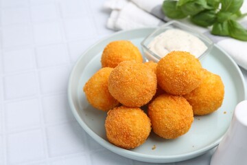 Delicious fried croquette balls and sauce on light tiled table, closeup