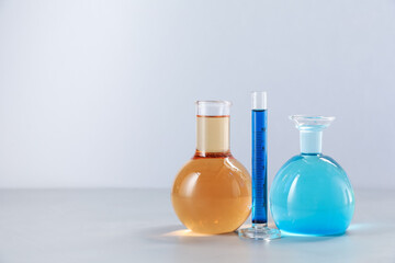 Different laboratory glassware with color liquids on light background. Space for text