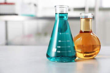 Flasks with color liquids on light table in laboratory. Space for text
