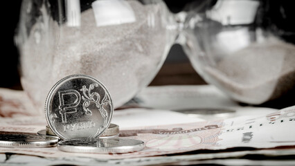 Russian ruble on the table with sand clock