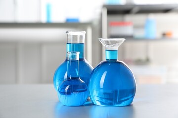 Flasks with light blue liquid on table in laboratory