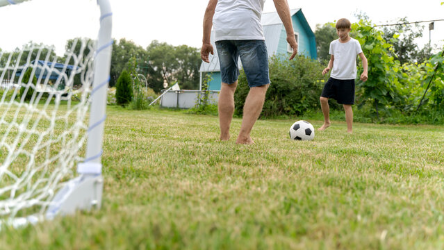 Grandson and grandfather playing football on grass