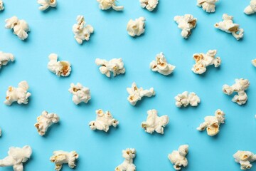 Tasty popcorn on light blue background, flat lay