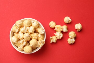 Tasty popcorn in bowl on red background, flat lay