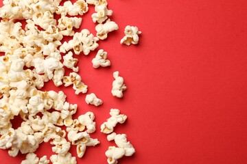 Tasty popcorn on red background, flat lay. Space for text