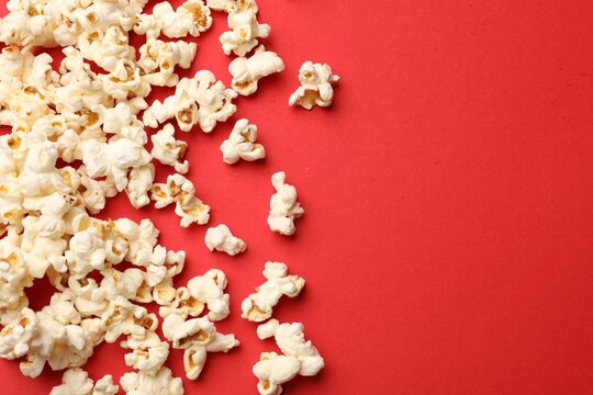 Tasty popcorn on red background, flat lay. Space for text