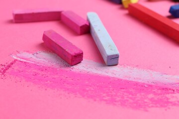Many colorful chalk pastels on pink background, closeup