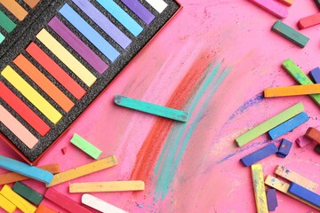 Many colorful chalk pastels on pink background, flat lay