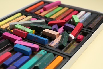 Set of colorful chalk pastels on beige background, closeup