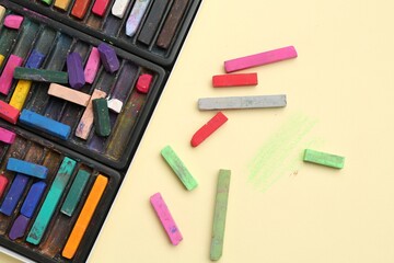 Many colorful chalk pastels on beige background, flat lay