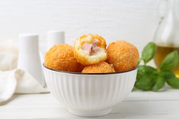 Delicious fried croquette balls in bowl on white wooden table, closeup