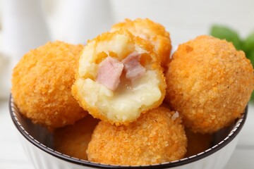 Delicious fried croquette balls in bowl on table, closeup