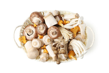 Different raw mushrooms in wicker basket isolated on white, top view