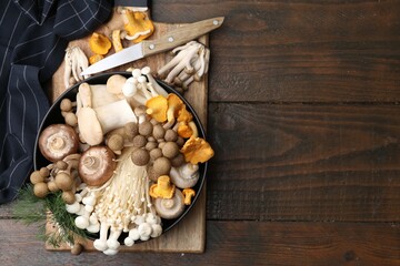 Fototapeta premium Different raw mushrooms in bowl and knife on wooden table, top view. Space for text